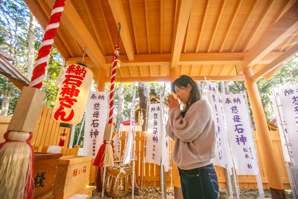 A woman prays to Ishigami-san at Shinmei Shrine.